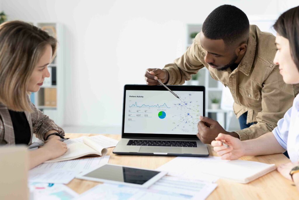 Afro-American marketer pointing at laptop screen while reporting marketing statistics at meeting